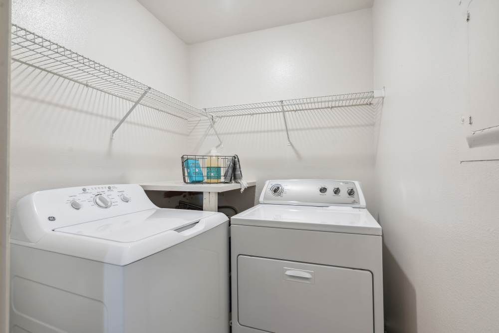 Laundry room with a washer, a dryer, and wire shelves.