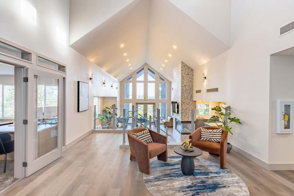 Bright, modern lobby seating area with a vaulted ceiling, large windows, and glass railings.