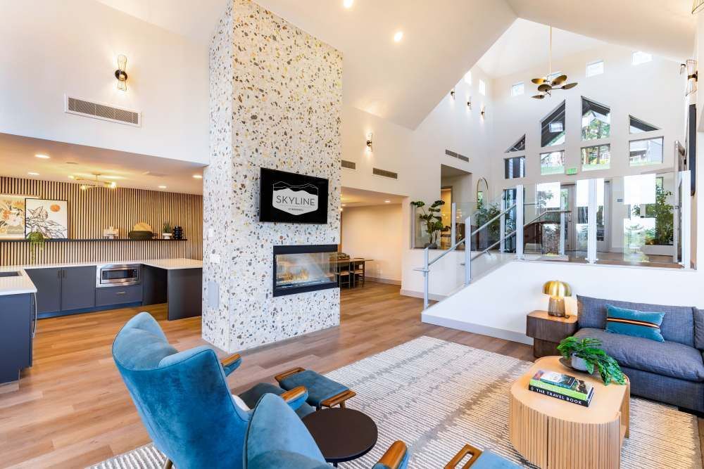 Bright communal lobby with contemporary seating, a fireplace, and a staircase to an upper level.