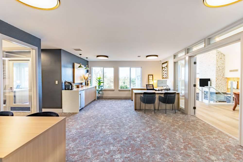Spacious building lobby with a reception desk, seating, and large windows.