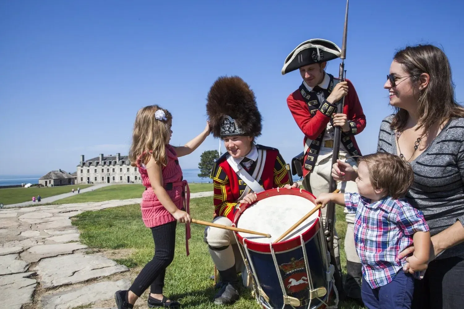 A group of people are standing around a man playing a drum.