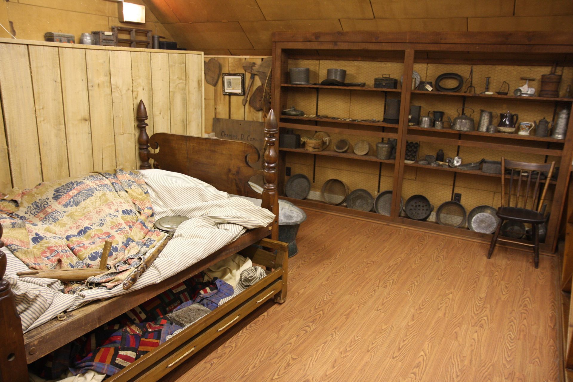 A bedroom with a bed and shelves filled with antique items