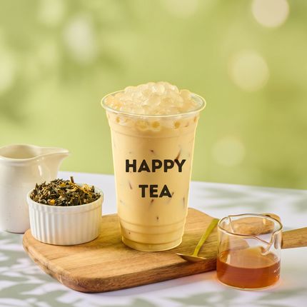 Happy Tea cup with iced tea, tea leaves, and a small glass on a wooden board against a soft green background
