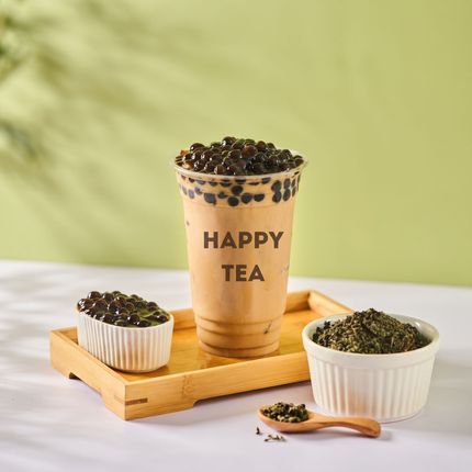 “HAPPY TEA” cup with tapioca pearls on a wooden tray, beside two small bowls and a spoon