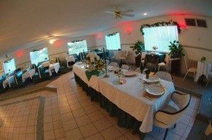 Banquet hall with a long set dining table, white tablecloths, chairs, and colorful ceiling lights