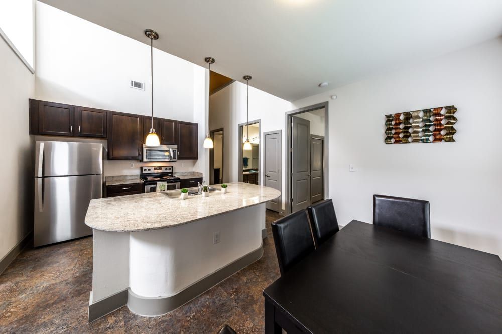 Apartment kitchen with stainless steel appliances and a dining table at Regents West at 26th in Austin, TX, near UT Austin.
