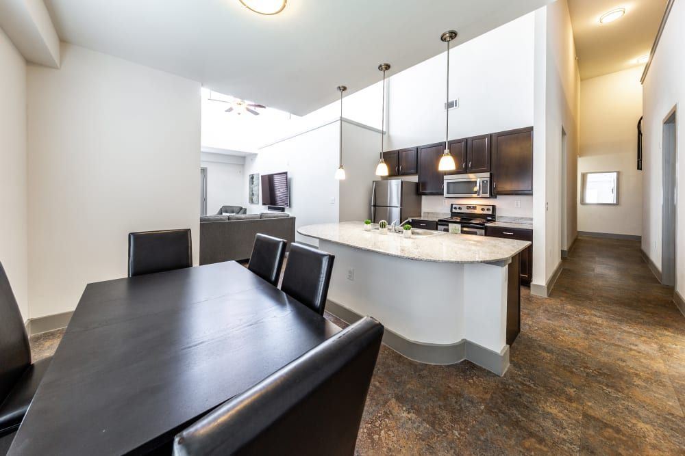 Apartment dining room with a table and chairs and a kitchen in the background at Regents West at 26th in Austin, TX, near UT Austin.