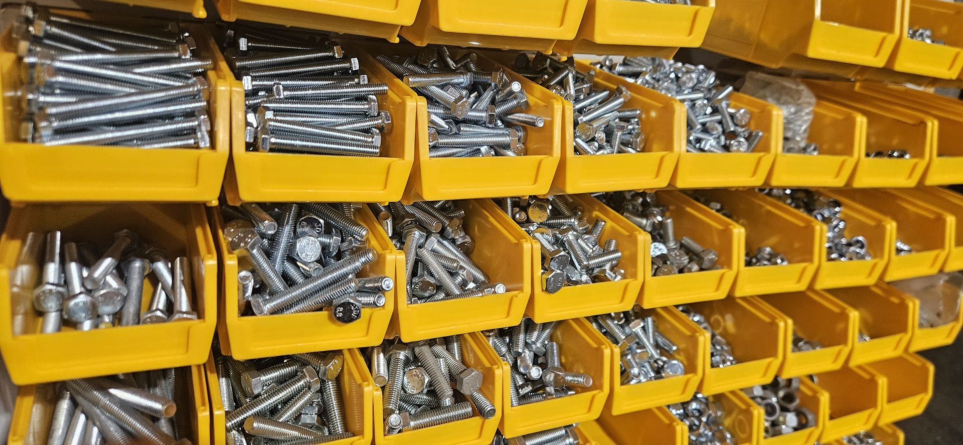 Yellow bins filled with assorted metal hardware parts on a storage rack