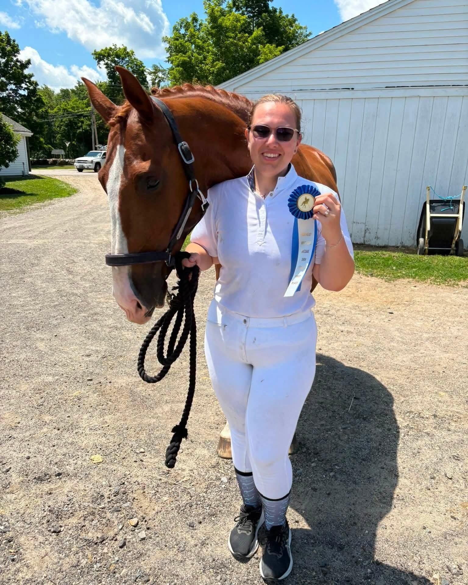 Rider posing with horse and a competition ribbon