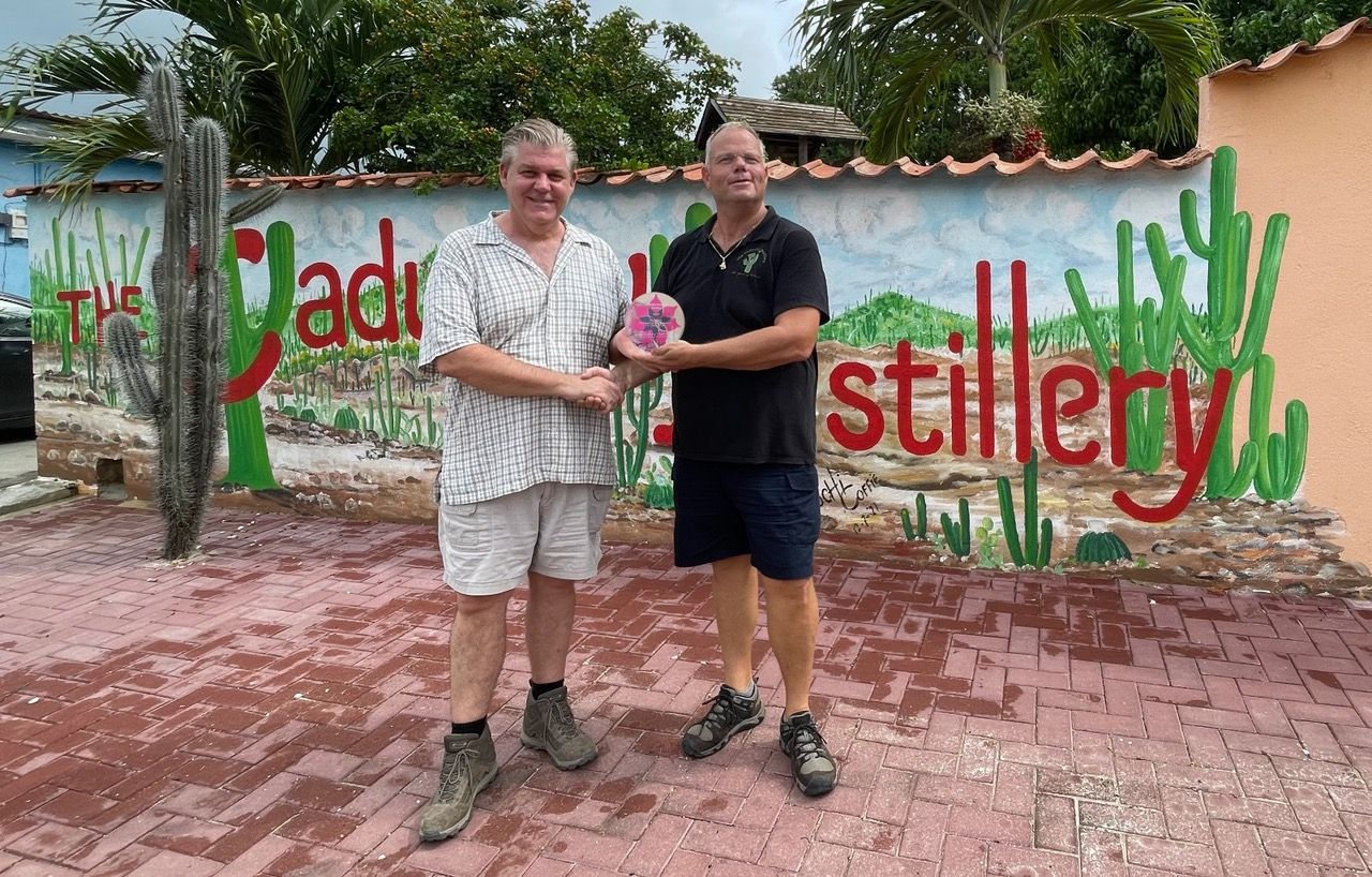 Two men are standing in front of a wall that says stillery