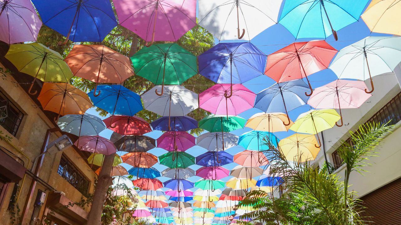 A bunch of colorful umbrellas are hanging from the ceiling of a building.