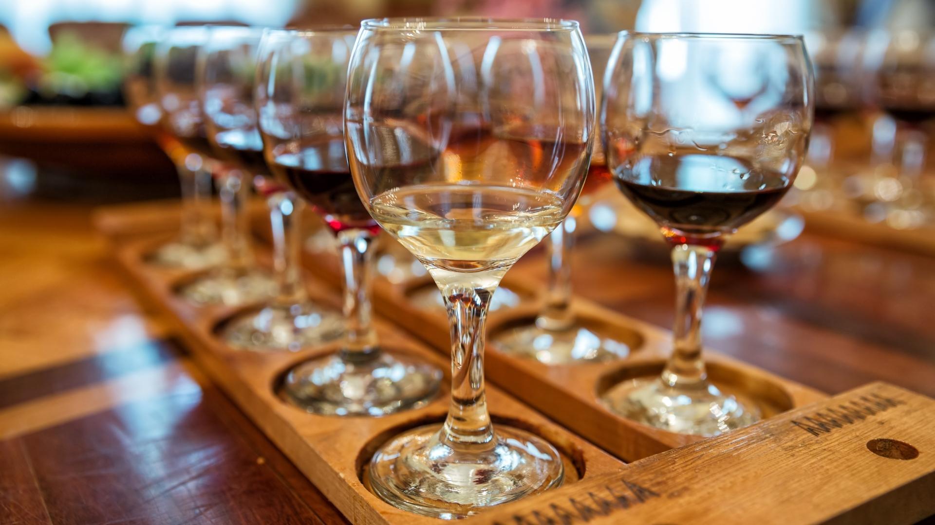 A wooden tray filled with glasses of wine on a wooden table.