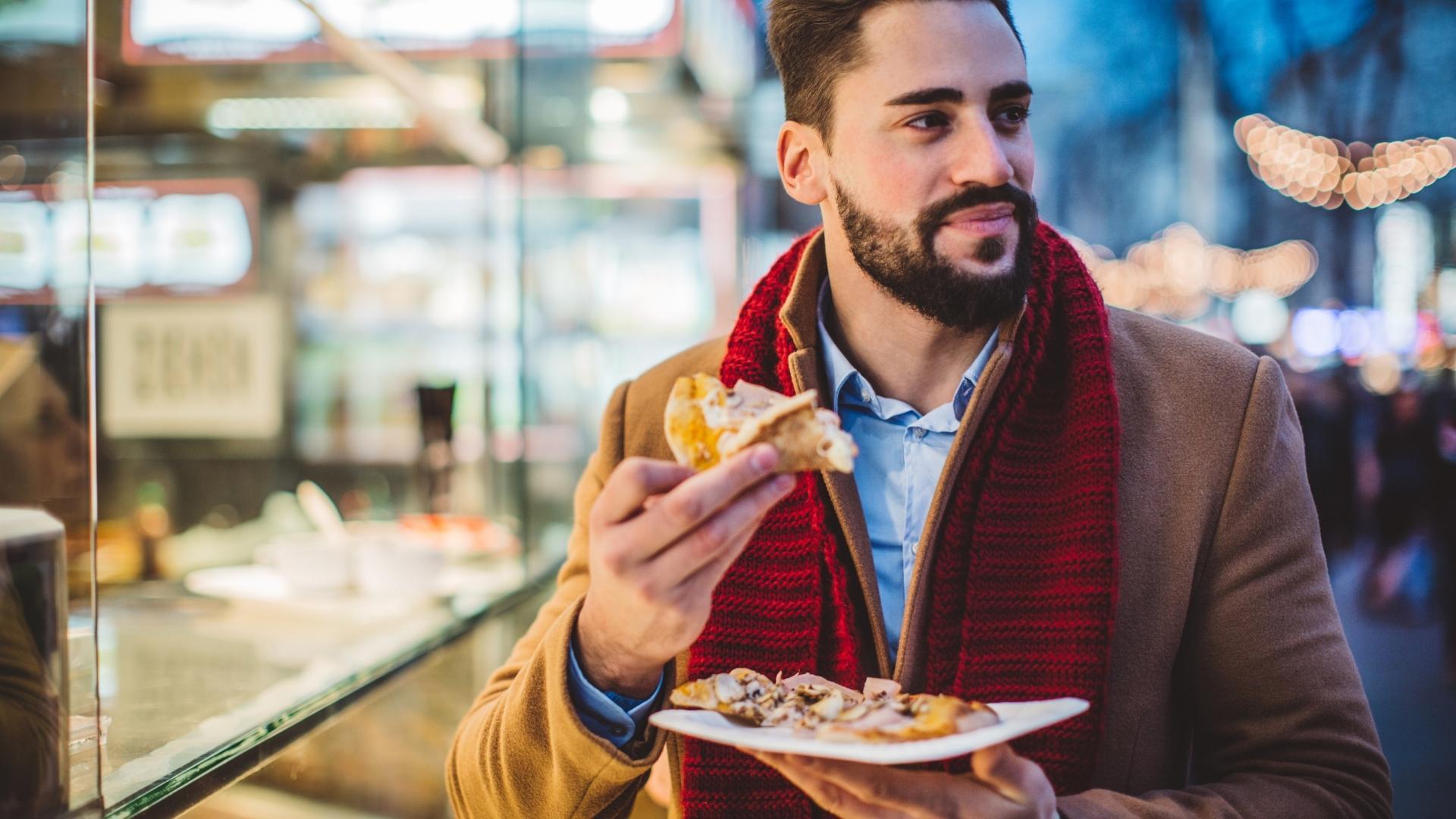A man is eating a slice of pizza from a plate.