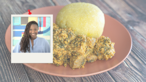 A woman is standing next to a plate of food on a wooden table.