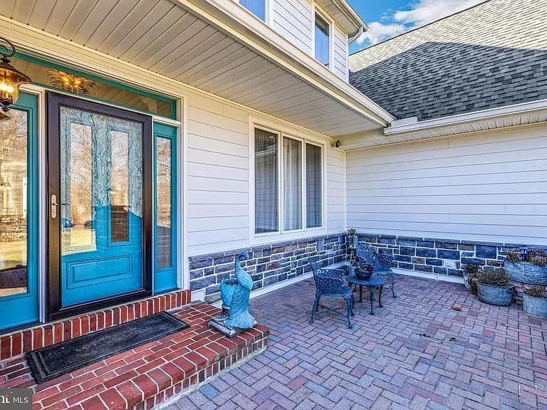 The front door of a house with a blue door and a brick patio.