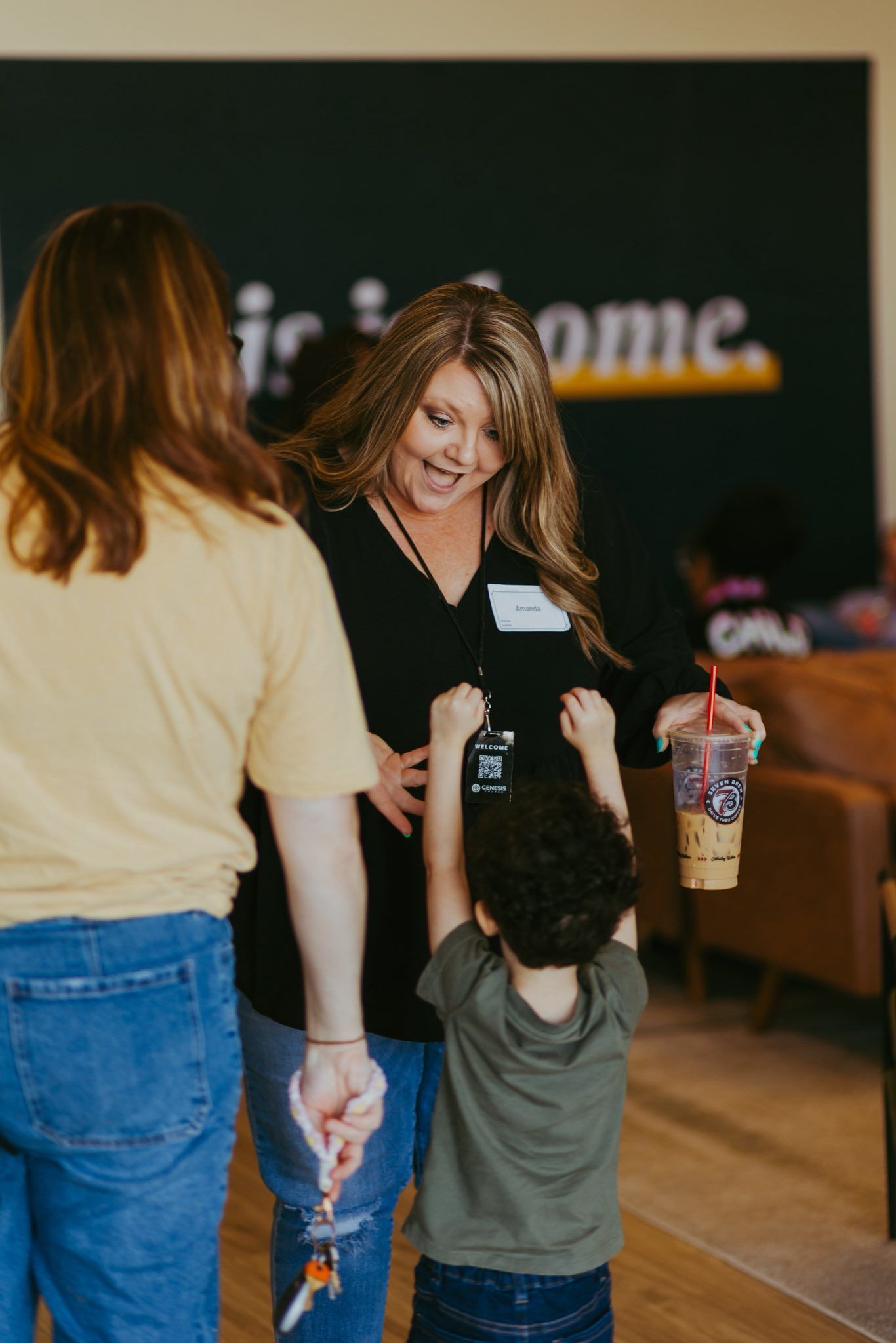 Woman handing a drink to a child reaching up in a café or restaurant setting