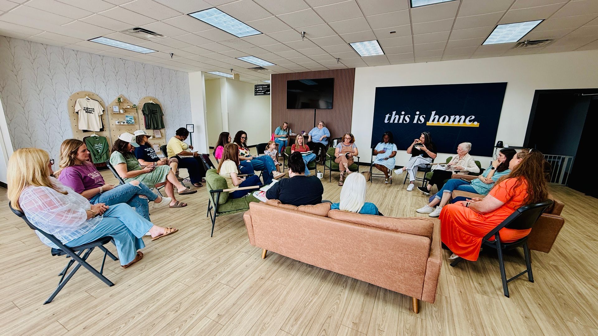 People seated in a bright conference room, meeting around a TV screen with “this is huma” on display.