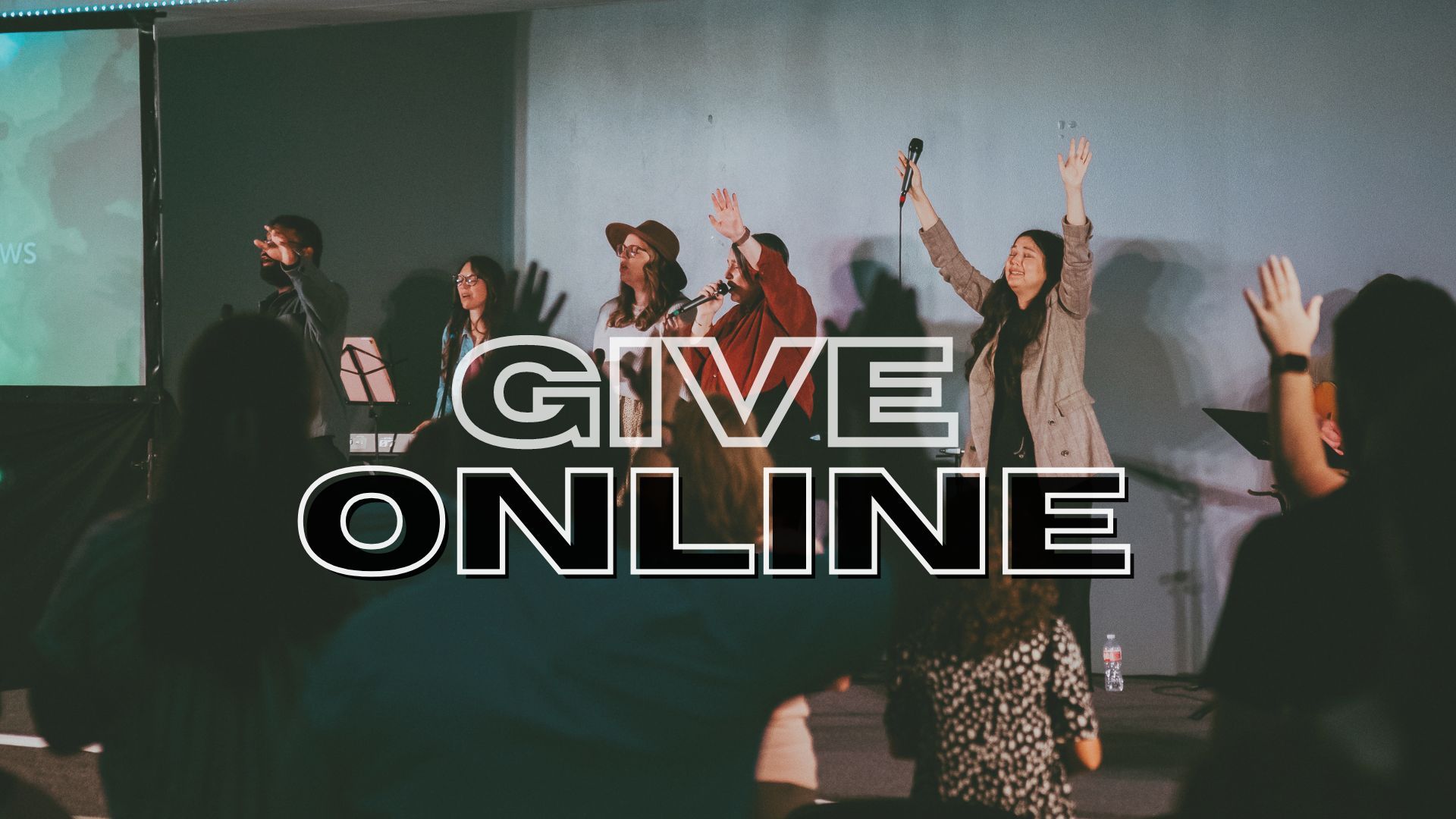 People in a church worship band, arms raised, 