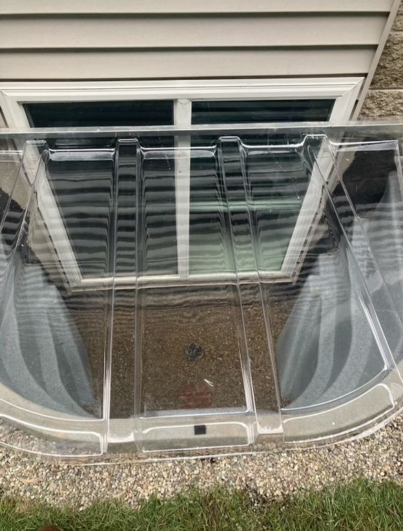 A picture of a window well with a clear cover on it.