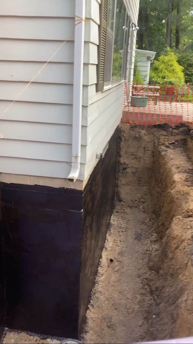 A white house with a black foundation is being remodeled.