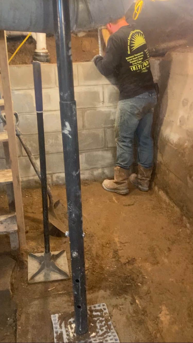 A man is working on a brick wall in a basement.