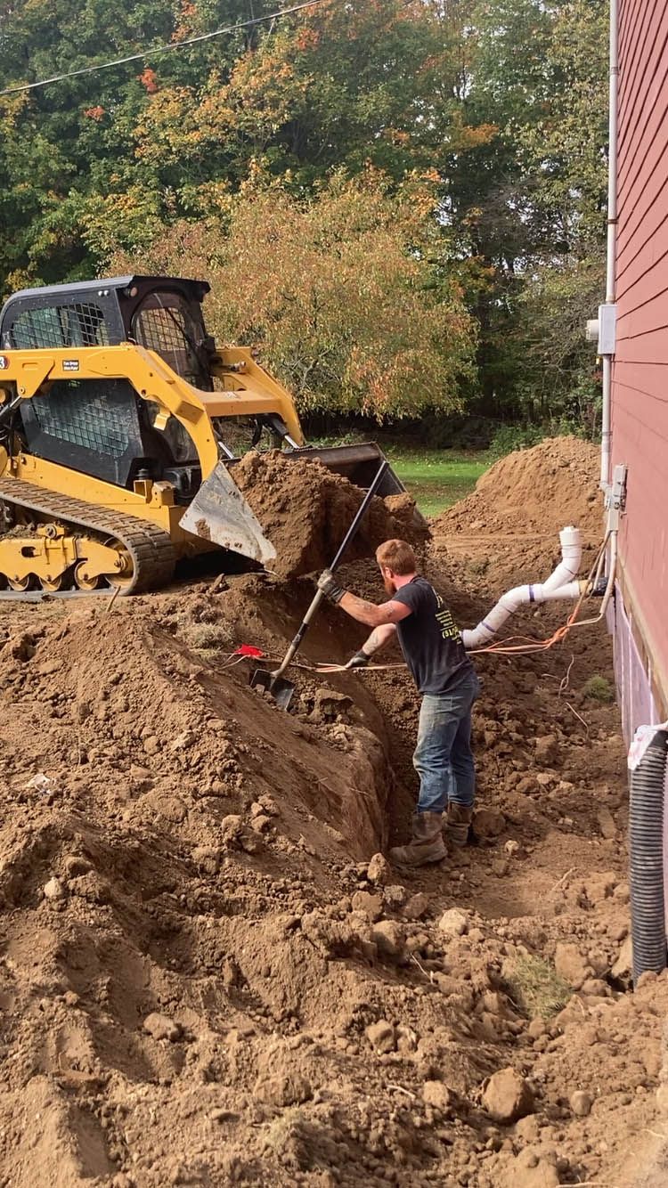 A man is digging a hole in the dirt next to a bulldozer.