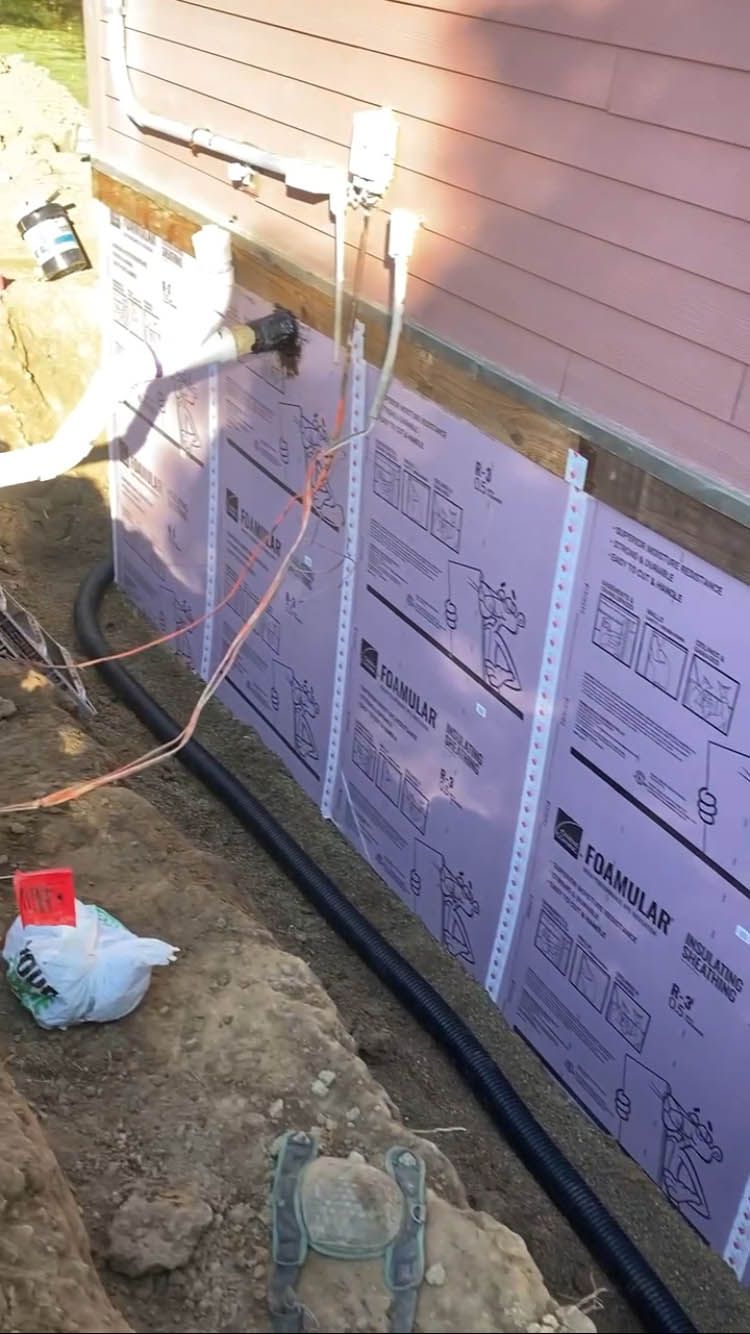 A drainage system is being installed on the side of a house.