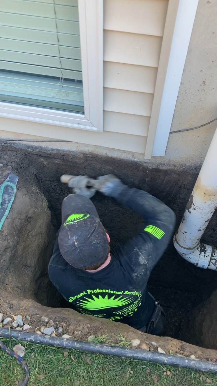 A man is digging a hole in the ground in front of a house.