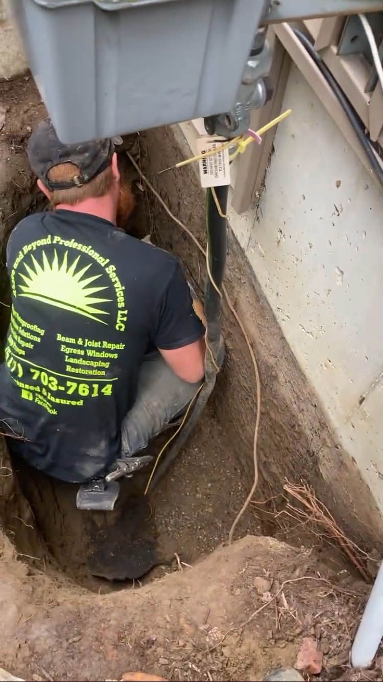 A man in a black shirt is kneeling in a hole in the ground.