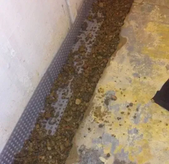 A pile of dirt is sitting on the ground next to a wall.