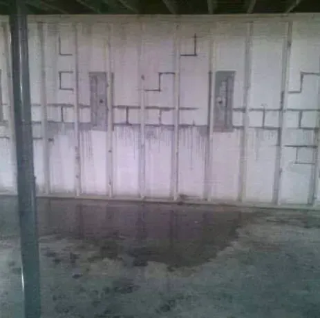 A basement with a white wall and a concrete floor.