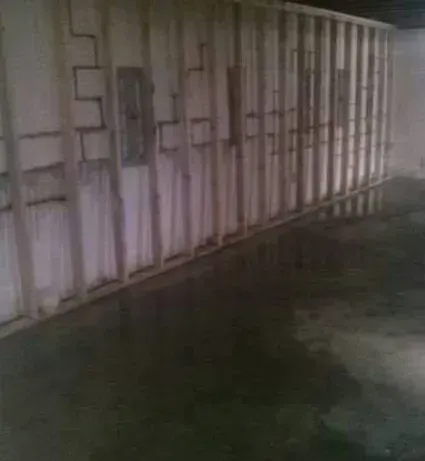 A basement with a concrete floor and a wall with wooden beams.