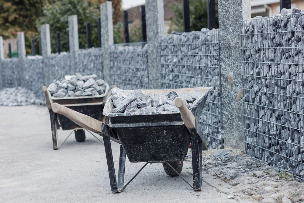 Two Wheelbarrows Filled With Rocks Are Parked In Front Of A Stone Wall — Twin Towns Sand & Gravel In Tweed Heads South, NSW