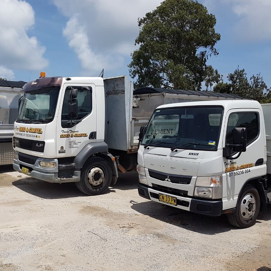 Two White Trucks Are Parked Next To Each Other On A Dirt Road — Twin Towns Sand & Gravel In Tweed Heads South, NSW