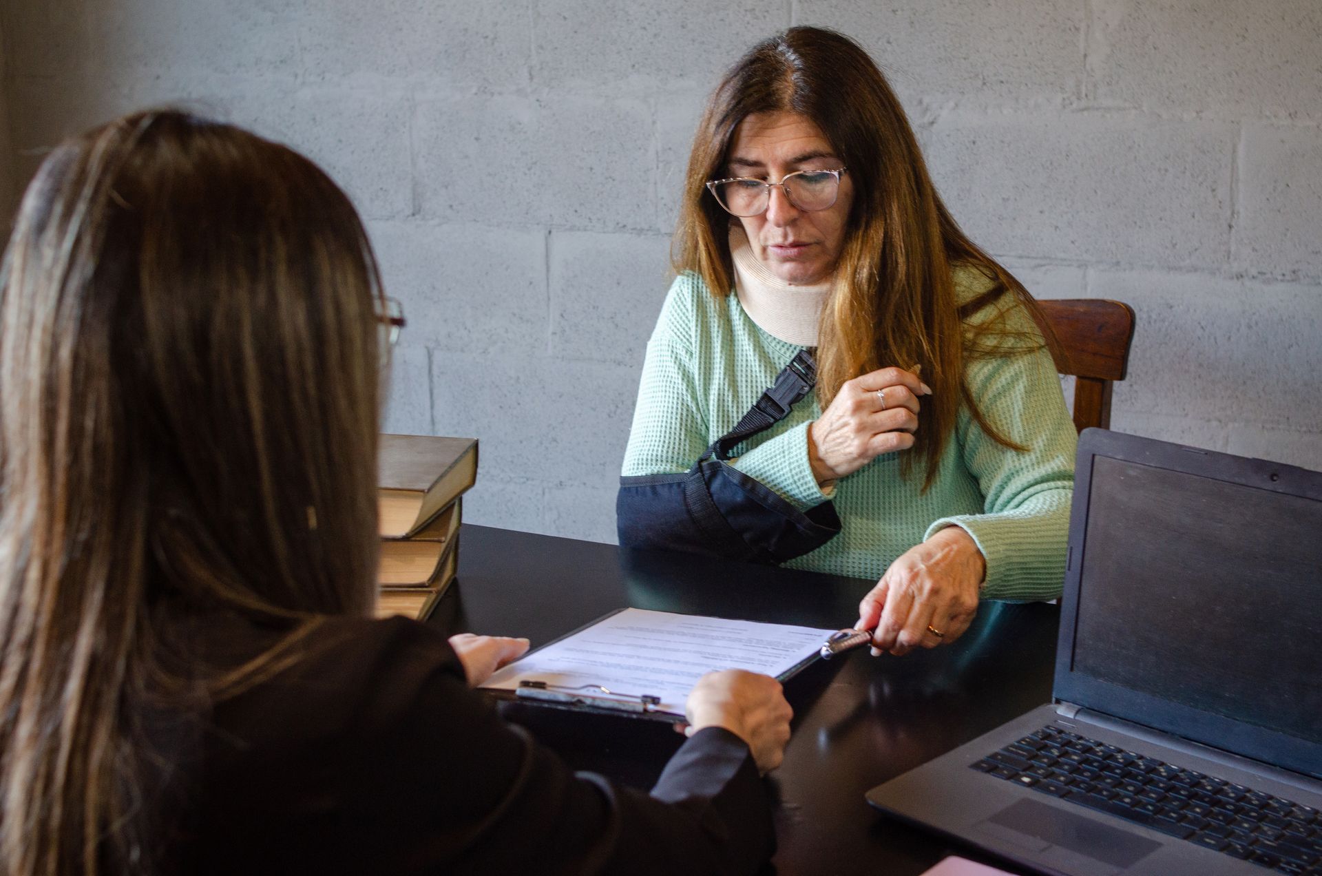 An injured client with an arm in a sling reviewing legal paperwork with an attorney