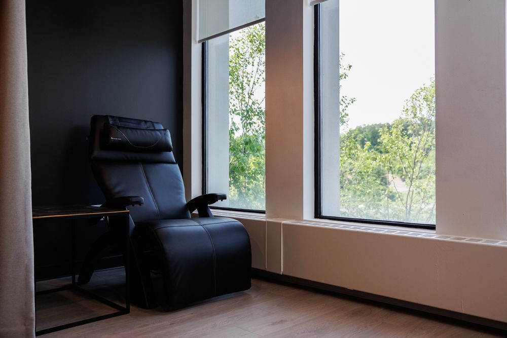A black chair is sitting in a room next to a window.