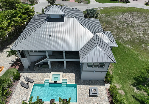 Modern house with silver metal roof, pool, and deck, viewed from above.