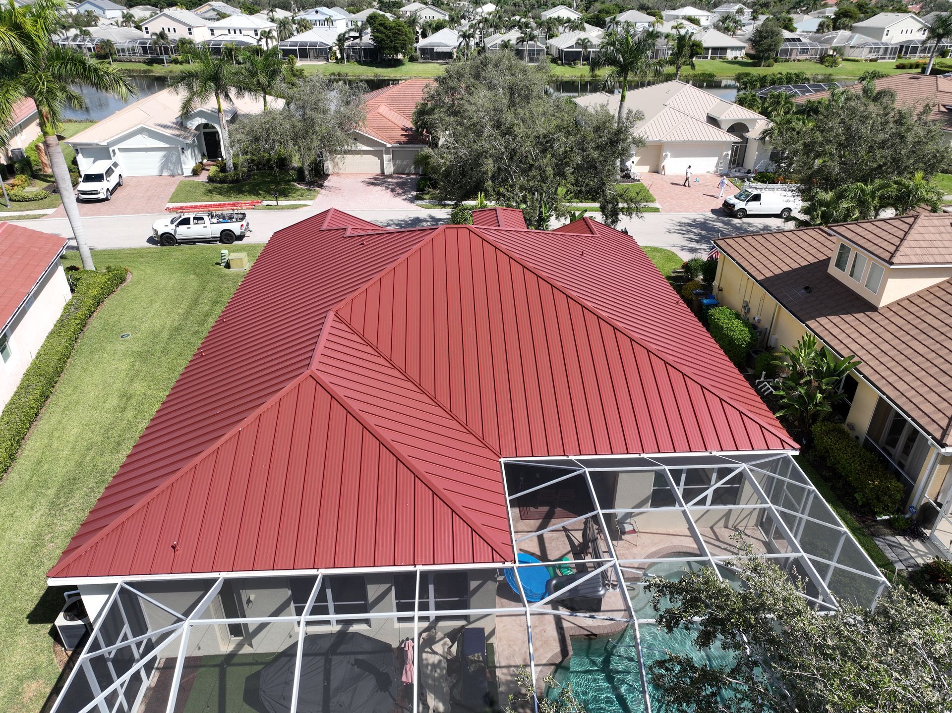 Red metal roof on a house with a screened-in pool, seen from above.