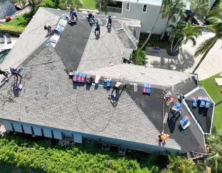Roofers working on a residential roof, surrounded by materials and safety lines.