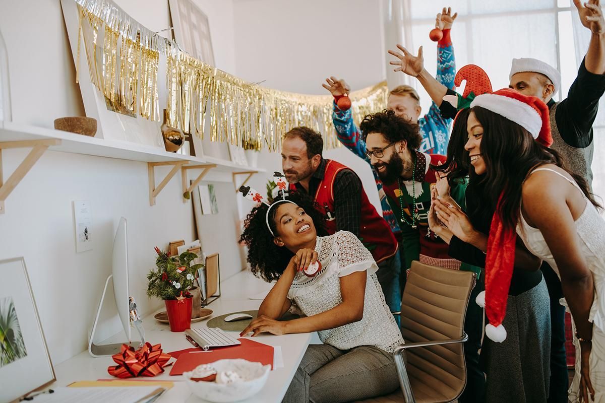 Friends celebrating at a decorated table with holiday hats, confetti, and raised glasses in a festive room