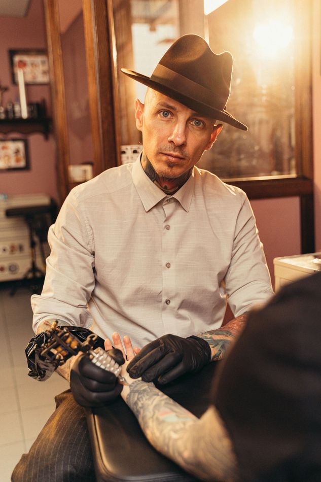 Male tattoo artist  takes a pause from inking a client's arm in Noblesville, Indiana