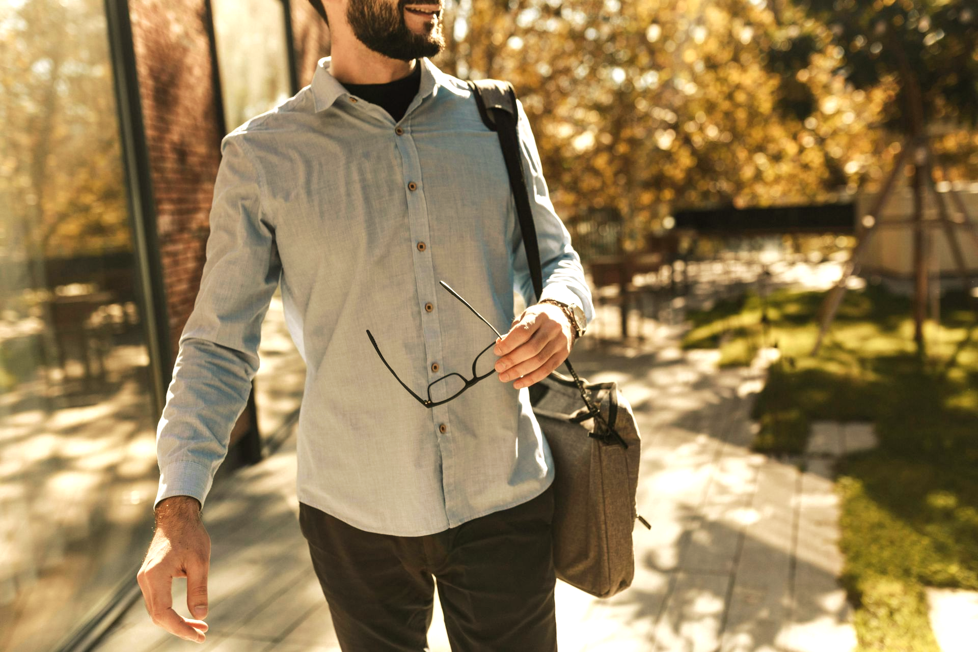 Man carrying his laptop and holding glasses during a morning walk in Fishers, Indiana