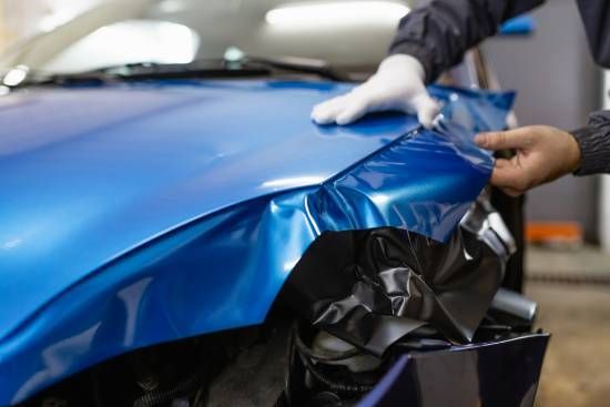 A Person is Wrapping a Blue Car With a Blue Wrap — High Grade Tyre and Mechanical in Toowoomba City, QLD