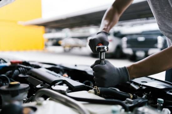 A Man is Working on the Engine of a Car With a Wrench — High Grade Tyre and Mechanical in Toowoomba City, QLD