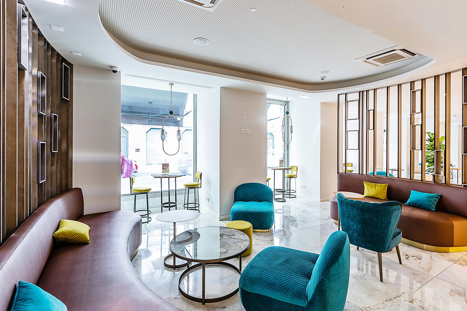 Modern hotel lobby with teal chairs, brown sofa, and marble floors.