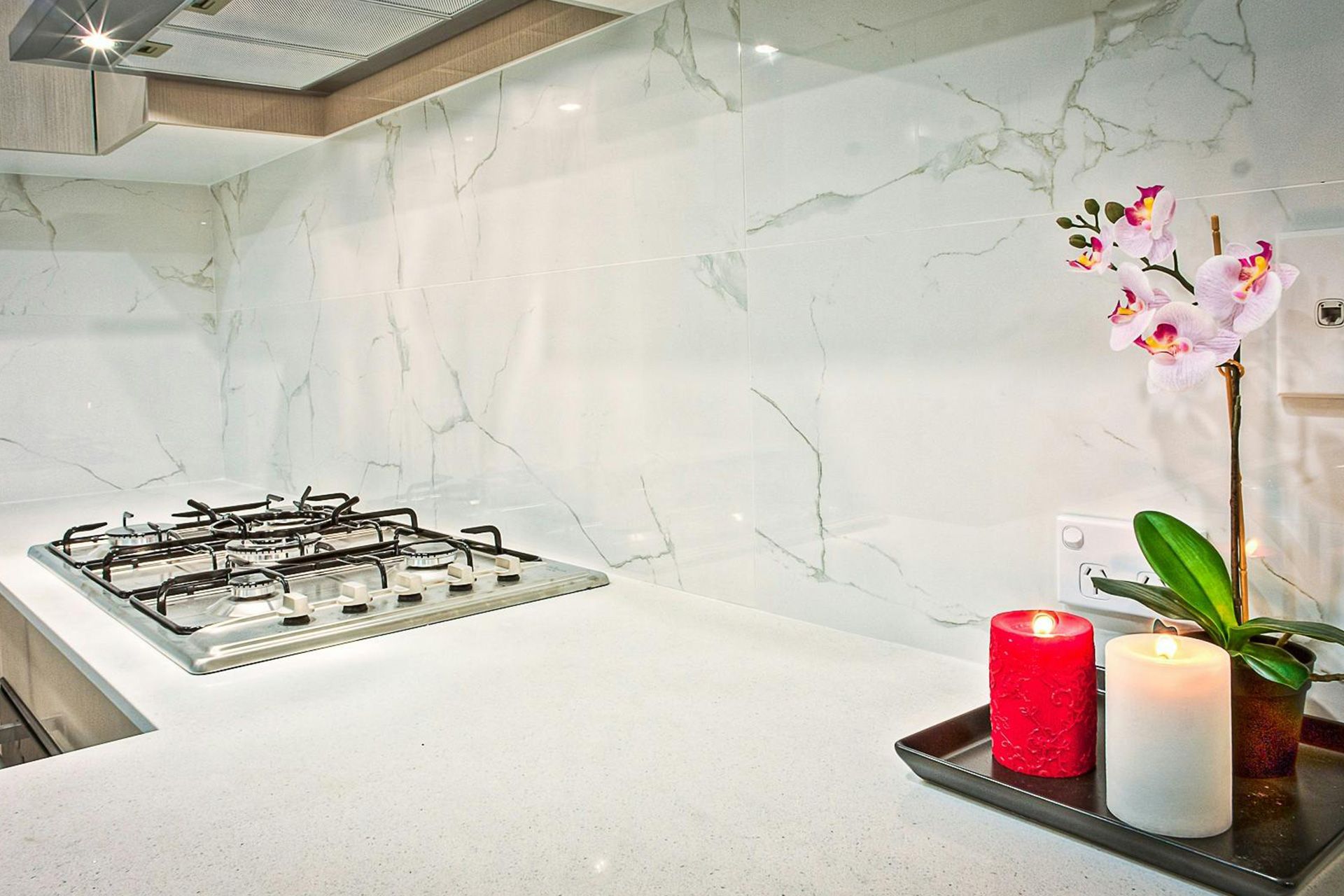 Kitchen with marble backsplash, cooktop, candles, and orchid.