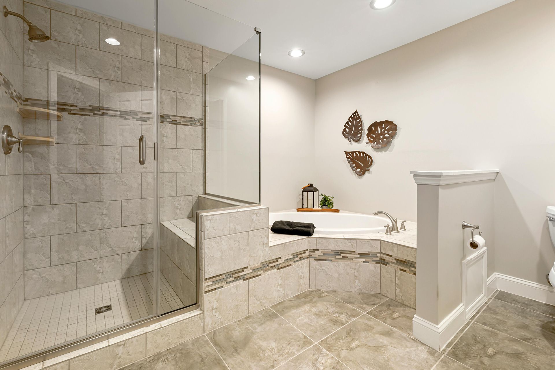 Bathroom with a glass-enclosed shower, built-in tub, beige tiles, and decorative wall art.