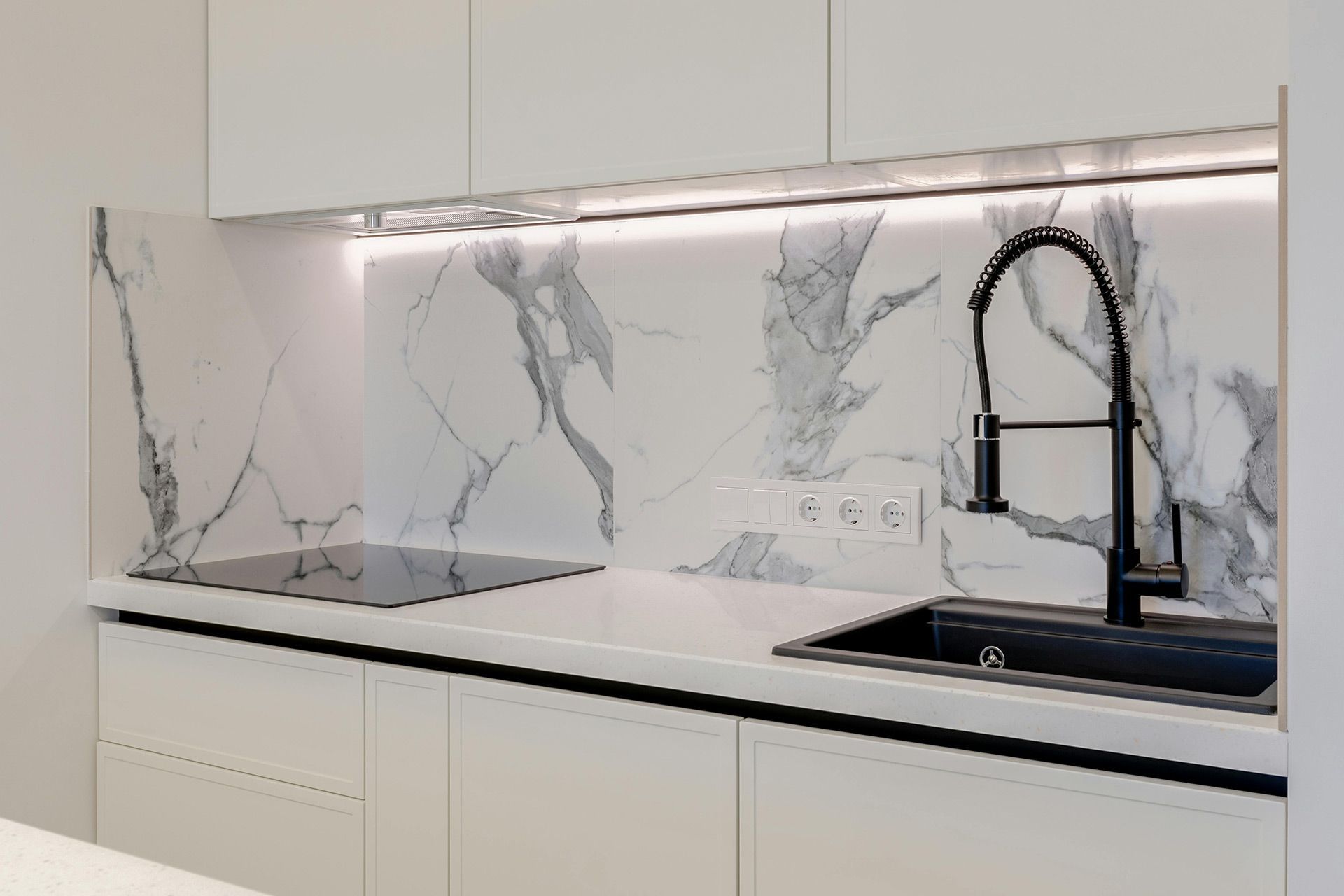 Modern kitchen with a marble porcelain slab backsplash installed behind a sink and cooktop in Lakewood Ohio.