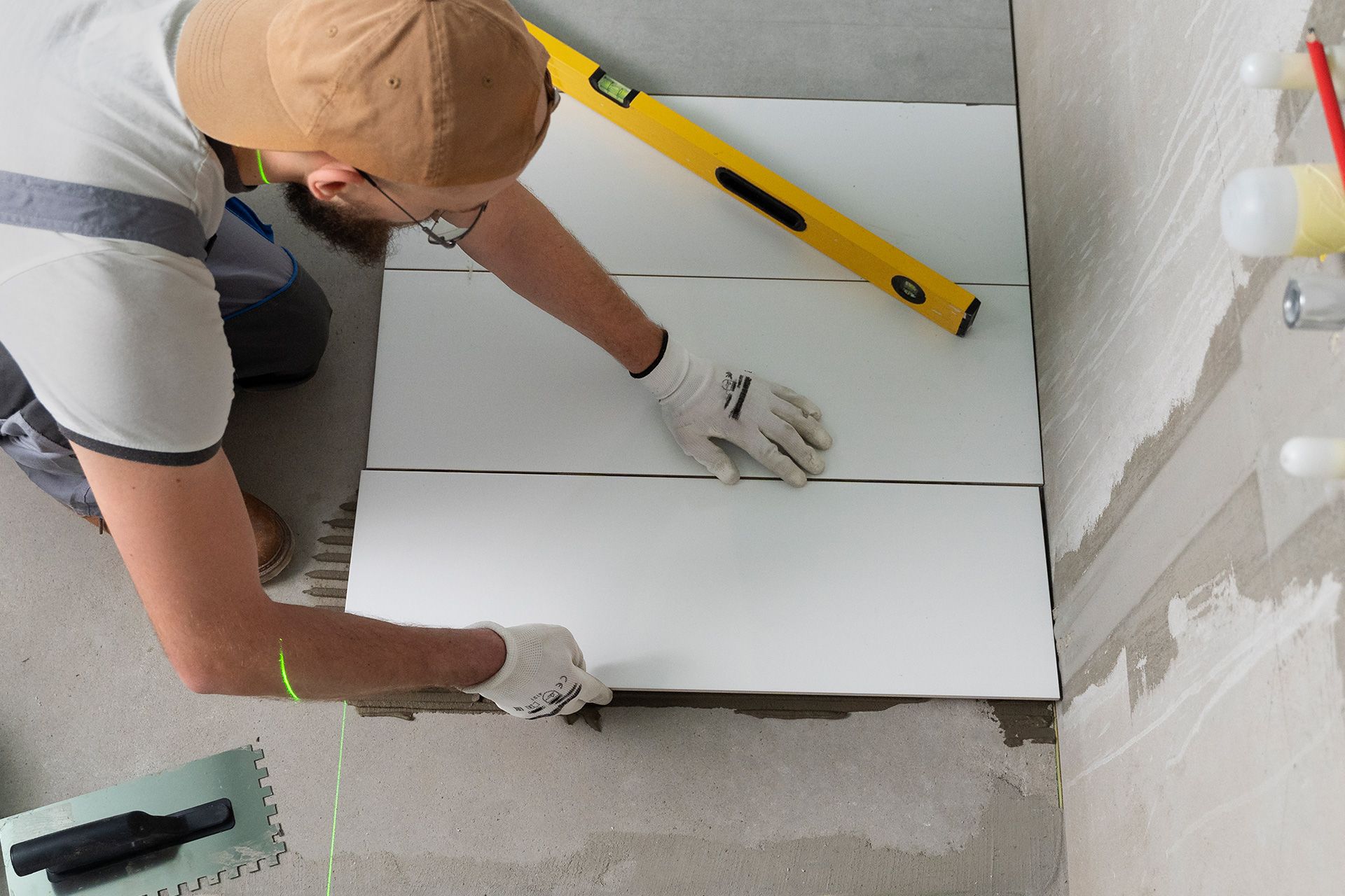 Professional installer placing large floor tile using a spirit level and trowel in Lakewood OH
