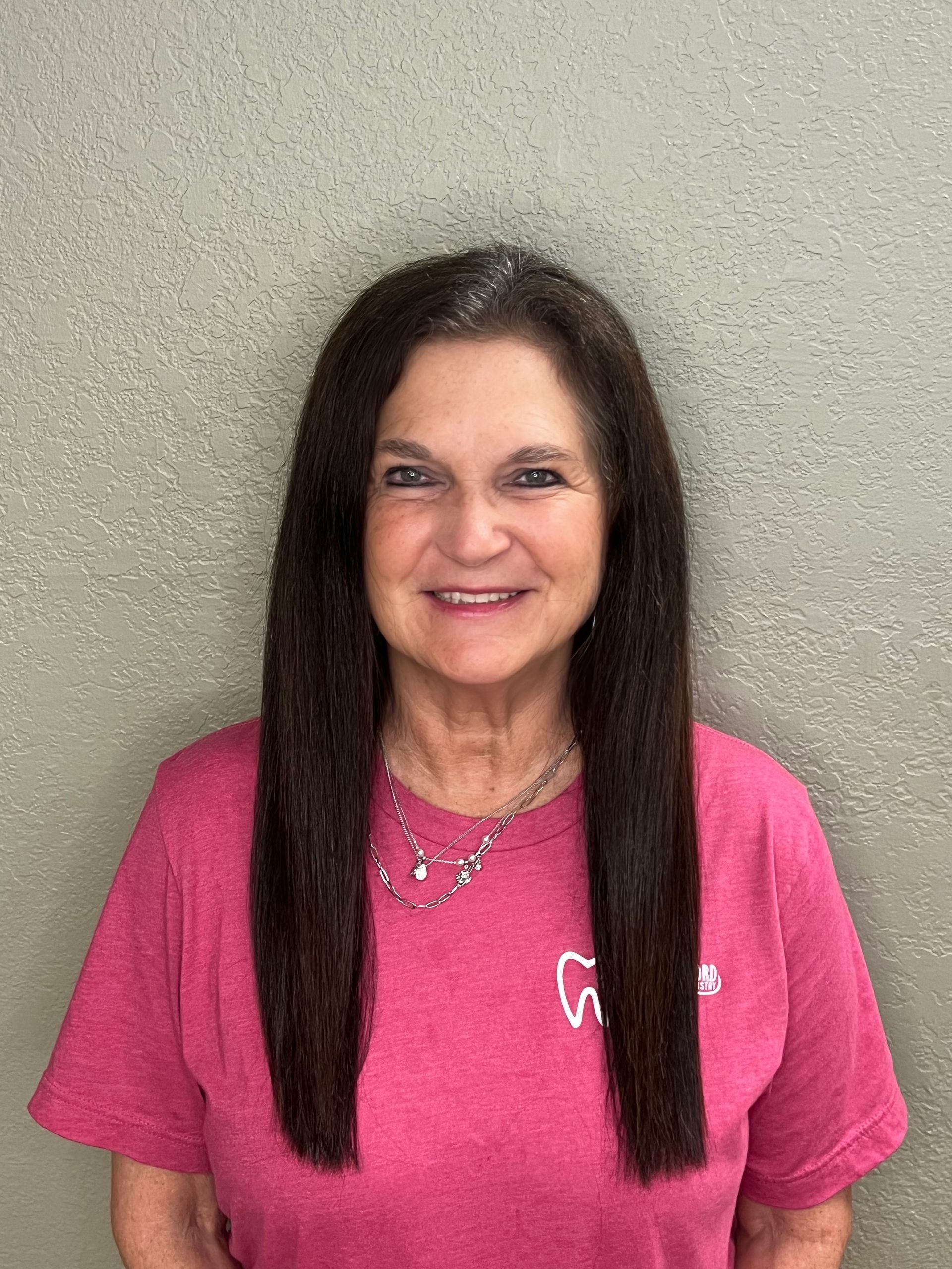 A woman in a green shirt is smiling for the camera.